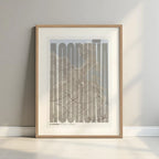 Framed A Coruña in Extra Compressed design, where the letters are tightly squeezed to fit the city's map shape designed in light brown and an off-white background with a white margin border in a warm lit minimalist setting