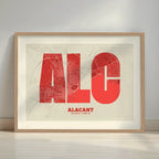 Framed Alacant in Super Bold design, a typographic poster where the city map is overlaid with extra-thick lettering for a modern, high-impact look designed in red and an off-white background with a white margin border in a warm lit minimalist setting