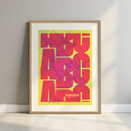 Framed Albacete in Inseparable design, featuring the city's abbreviation in expressive typography over a detailed urban map designed in yellow and fuchsia with a white margin border in a warm lit minimalist setting