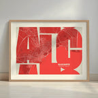Framed Alicante in Inseparable design, featuring the city's abbreviation in expressive typography over a detailed urban map designed in red and an off-white background with a white margin border in a warm lit minimalist setting