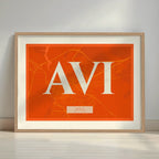 Framed Avila in Classic design, inspired by chiseled typography with an elegant font that creates a beautiful visual contrast designed in orange and an off-white background with a white margin border in a warm lit minimalist setting