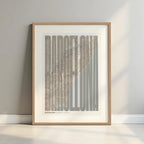 Framed Barcelona in Extra Compressed design, where the letters are tightly squeezed to fit the city's map shape designed in light brown and an off-white background with a white margin border in a warm lit minimalist setting
