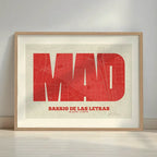 Framed Barrio de Las Letras in Super Bold design, a typographic poster where the city map is overlaid with extra-thick lettering for a modern, high-impact look designed in red and an off-white background with a white margin border in a warm lit minimalist setting