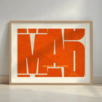 Framed Barrio de Las Letras in Inseparable design, featuring the city's abbreviation in expressive typography over a detailed urban map designed in orange and an off-white background with a white margin border in a warm lit minimalist setting