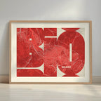 Framed Bilbao in Inseparable design, featuring the city's abbreviation in expressive typography over a detailed urban map designed in red and an off-white background with a white margin border in a warm lit minimalist setting