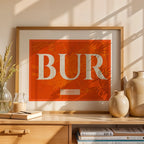Modern interior design with a Burgos in Classic design, inspired by chiseled typography with an elegant font that creates a beautiful visual contrast designed in orange and an off-white background, displayed on a living room wall