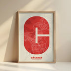 Framed Caceres in Super Bold design, a typographic poster where the city map is overlaid with extra-thick lettering for a modern, high-impact look designed in red and an off-white background with no border edge-to-edge print leaning against a wall