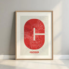 Framed Caceres in Super Bold design, a typographic poster where the city map is overlaid with extra-thick lettering for a modern, high-impact look designed in red and an off-white background with a white margin border in a warm lit minimalist setting