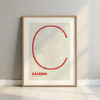 Framed Caceres in Ultralight design, a minimalist aesthetic combining urban cartography with modern, extra-thin elegant lettering designed in red and an off-white background with a white margin border in a warm lit minimalist setting