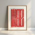 Framed Caceres in Extra Compressed design, where the letters are tightly squeezed to fit the city's map shape designed in red and an off-white background with a white margin border in a warm lit minimalist setting