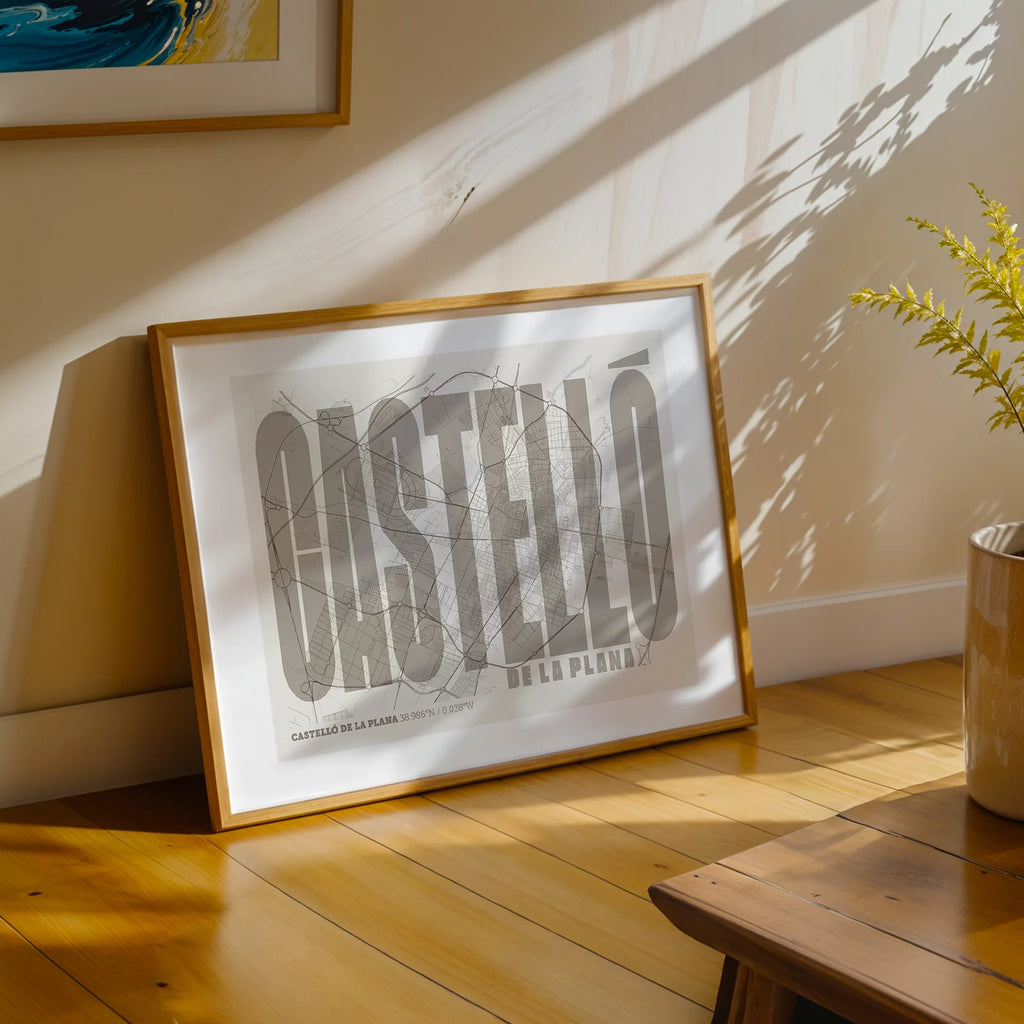 Diseño de interiores moderno con la lámina de Castellón en el diseño la Extra Comprimida, donde las letras se ajustan al ancho del mapa de la ciudad diseñado en marrón claro y fondo blanco roto, expuesto en la pared de un salón