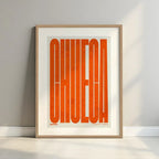 Cuadro de Chueca, Madrid, en el diseño la Extra Comprimida, donde las letras se ajustan al ancho del mapa de la ciudad diseñado en naranja y fondo blanco roto con margen en un entorno minimalista con iluminación cálida