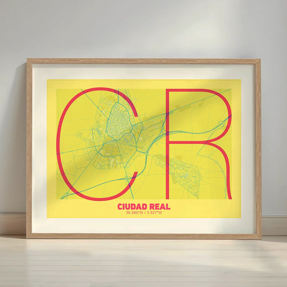 Framed Ciudad Real in Ultralight design, a minimalist aesthetic combining urban cartography with modern, extra-thin elegant lettering designed in yellow and fuchsia with a white margin border in a warm lit minimalist setting