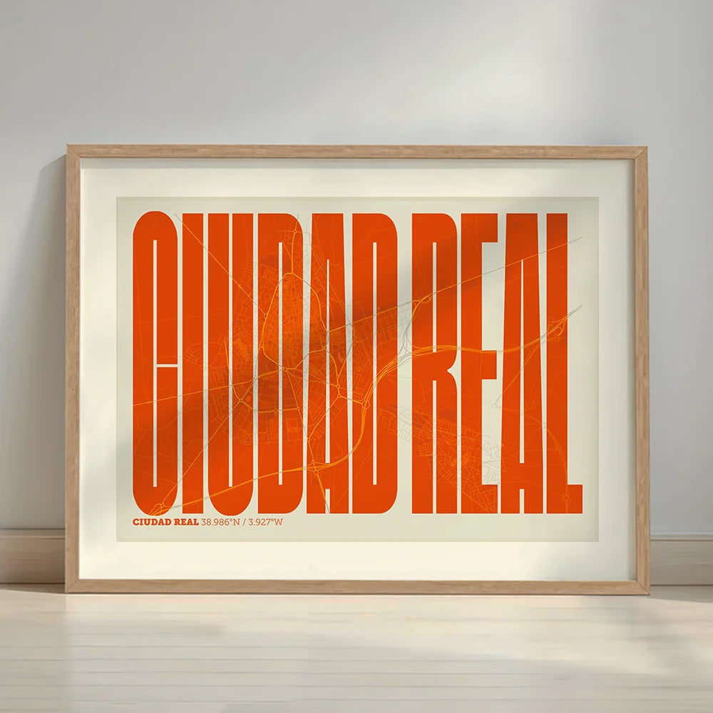 Framed Ciudad Real in Extra Compressed design, where the letters are tightly squeezed to fit the city's map shape designed in orange and an off-white background with a white margin border in a warm lit minimalist setting