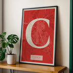 Modern interior design with a Cuenca in Classic design, inspired by chiseled typography with an elegant font that creates a beautiful visual contrast designed in red and an off-white background, displayed on a living room wall