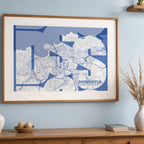 Diseño de interiores moderno con la lámina de Donostia en mi diseño la Inseparable, una visión artística con una tipografía expresiva que muestra la abreviatura del nombre sobre el mapa detallado diseñado en azul marino y blanco, expuesto en la pared de un salón