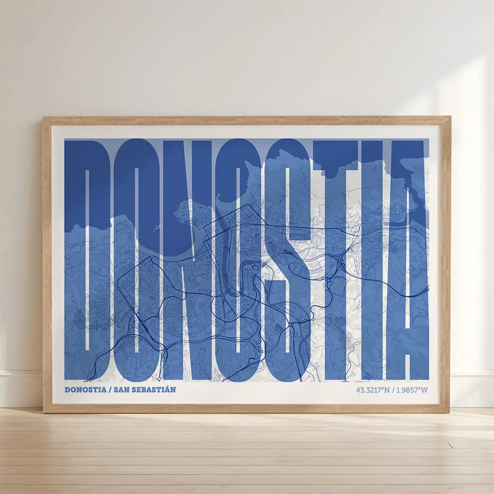 Cuadro de Donostia en el diseño la Extra Comprimida, donde las letras se ajustan al ancho del mapa de la ciudad diseñado en azul marino y blanco con impresión sin márgenes, apoyado contra la pared