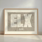 Framed Elche in Super Bold design, a typographic poster where the city map is overlaid with extra-thick lettering for a modern, high-impact look designed in light brown and an off-white background with a white margin border in a warm lit minimalist setting