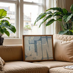 Modern interior design with a Gijon in Inseparable design, featuring the city's abbreviation in expressive typography over a detailed urban map designed in bluish gray and an off-white background, displayed on a living room wall
