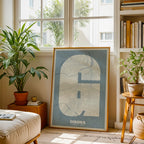 Modern interior design with a Girona in Super Bold design, a typographic poster where the city map is overlaid with extra-thick lettering for a modern, high-impact look designed in bluish gray and an off-white background, displayed on a living room wall