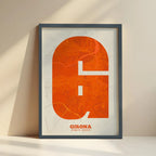 Framed Girona in Super Bold design, a typographic poster where the city map is overlaid with extra-thick lettering for a modern, high-impact look designed in orange and an off-white background with no border edge-to-edge print leaning against a wall