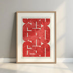 Framed Girona in Inseparable design, featuring the city's abbreviation in expressive typography over a detailed urban map designed in red and an off-white background with a white margin border in a warm lit minimalist setting