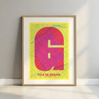 Framed Gracia Quarter in Super Bold design, a typographic poster where the city map is overlaid with extra-thick lettering for a modern, high-impact look designed in yellow and fuchsia with a white margin border in a warm lit minimalist setting