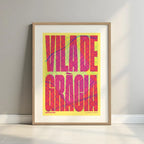 Framed Gracia Quarter in Extra Compressed design, where the letters are tightly squeezed to fit the city's map shape designed in yellow and fuchsia with a white margin border in a warm lit minimalist setting