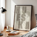 Diseño de interiores moderno con la lámina de Huesca en el diseño la Revoltosa, donde las letras del nombre aparecen aleatoriamente en diferentes líneas para un diseño urbano realmente original diseñado en marrón claro y fondo blanco roto, expuesto en la pared de un salón