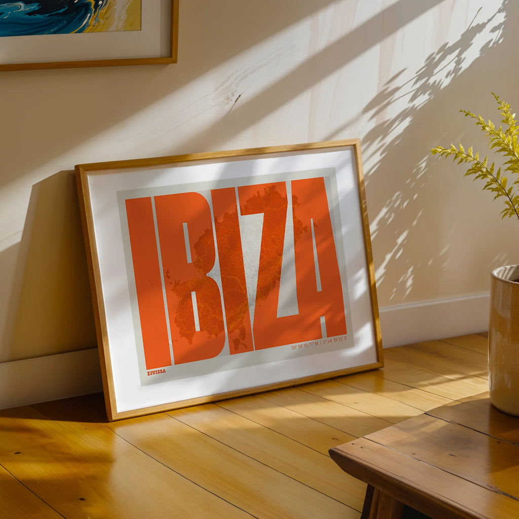 Modern interior design with a Ibiza in Extra Compressed design, where the letters are tightly squeezed to fit the city's map shape designed in orange and an off-white background, displayed on a living room wall