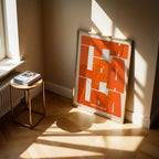 Modern interior design with a Las Palmas in Inseparable design, featuring the city's abbreviation in expressive typography over a detailed urban map designed in orange and an off-white background, displayed on a living room wall