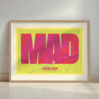 Framed Lavapies, Madrid, in Super Bold design, a typographic poster where the city map is overlaid with extra-thick lettering for a modern, high-impact look designed in yellow and fuchsia with a white margin border in a warm lit minimalist setting