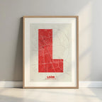 Framed Leon in Super Bold design, a typographic poster where the city map is overlaid with extra-thick lettering for a modern, high-impact look designed in red and an off-white background with a white margin border in a warm lit minimalist setting