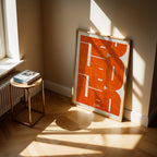 Modern interior design with a Leon in Inseparable design, featuring the city's abbreviation in expressive typography over a detailed urban map designed in orange and an off-white background, displayed on a living room wall