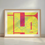 Framed Lleida in Inseparable design, featuring the city's abbreviation in expressive typography over a detailed urban map designed in yellow and fuchsia with a white margin border in a warm lit minimalist setting