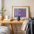 Modern interior design with a Lleida in Extra Compressed design, where the letters are tightly squeezed to fit the city's map shape designed in purple and light blue, displayed on a living room wall