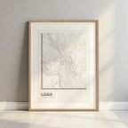Framed Lugo in Ultralight design, a minimalist aesthetic combining urban cartography with modern, extra-thin elegant lettering designed in light brown and an off-white background with a white margin border in a warm lit minimalist setting