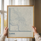 Diseño de interiores moderno con la lámina de Lugo en el diseño la Ultrafina, una estética minimalista que combina cartografía urbana con letras modernas, finas y elegantes diseñado en gris azulado y fondo blanco roto, expuesto en la pared de un salón