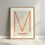 Framed Malasaña, Madrid, in Ultralight design, a minimalist aesthetic combining urban cartography with modern, extra-thin elegant lettering designed in orange and an off-white background with a white margin border in a warm lit minimalist setting