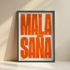 Framed Malasaña, Madrid, in Extra Compressed design, where the letters are tightly squeezed to fit the city's map shape designed in orange and an off-white background with no border edge-to-edge print leaning against a wall