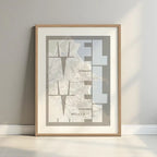 Framed Melilla in Inseparable design, featuring the city's abbreviation in expressive typography over a detailed urban map designed in light brown and an off-white background with a white margin border in a warm lit minimalist setting