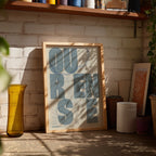 Diseño de interiores moderno con la lámina de Ourense en el diseño la Revoltosa, donde las letras del nombre aparecen aleatoriamente en diferentes líneas para un diseño urbano realmente original diseñado en gris azulado y fondo blanco roto, expuesto en la pared de un salón
