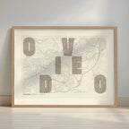 Framed Oviedo in Unruled design, where the city name letters appear randomly across different lines for a truly original urban layout designed in light brown and an off-white background with a white margin border in a warm lit minimalist setting