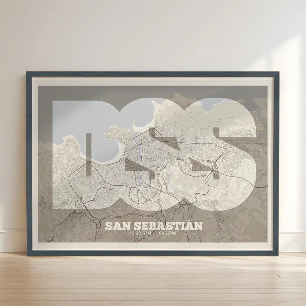 Framed San Sebastian in Super Bold design, a typographic poster where the city map is overlaid with extra-thick lettering for a modern, high-impact look designed in light brown and an off-white background with no border edge-to-edge print leaning against a wall