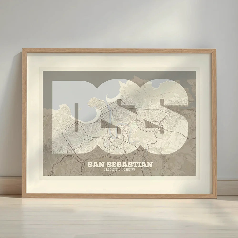 Framed San Sebastian in Super Bold design, a typographic poster where the city map is overlaid with extra-thick lettering for a modern, high-impact look designed in light brown and an off-white background with a white margin border in a warm lit minimalist setting