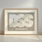 Framed San Sebastian in Super Bold design, a typographic poster where the city map is overlaid with extra-thick lettering for a modern, high-impact look designed in light brown and an off-white background with a white margin border in a warm lit minimalist setting