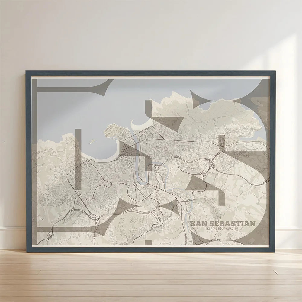 Framed San Sebastian in Inseparable design, featuring the city's abbreviation in expressive typography over a detailed urban map designed in light brown and an off-white background with no border edge-to-edge print leaning against a wall