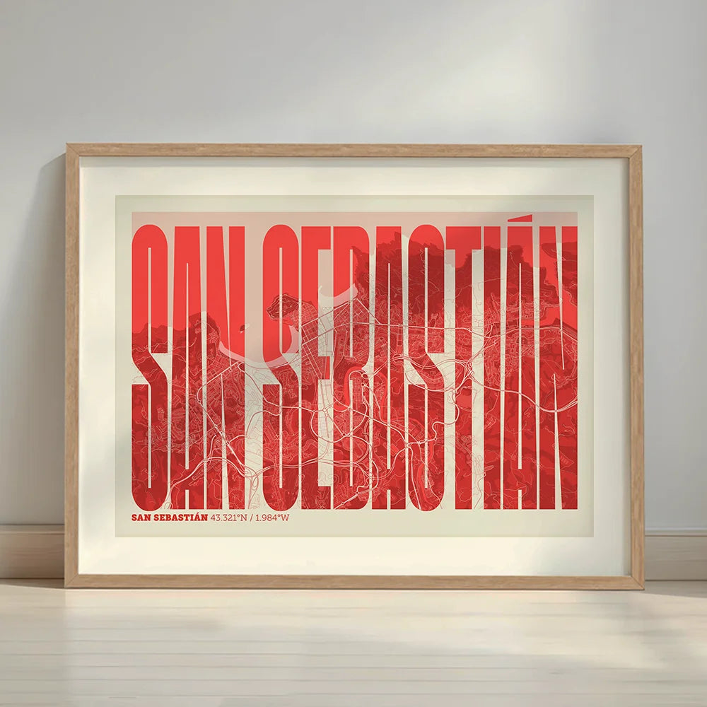 Framed San Sebastian in Extra Compressed design, where the letters are tightly squeezed to fit the city's map shape designed in red and an off-white background with a white margin border in a warm lit minimalist setting