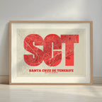 Framed Santa Cruz de Tenerife in Super Bold design, a typographic poster where the city map is overlaid with extra-thick lettering for a modern, high-impact look designed in red and an off-white background with a white margin border in a warm lit minimalist setting