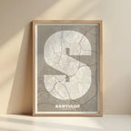 Cuadro de Santiago de Compostela en mi diseño la Súper Bold, un póster tipográfico donde el mapa de la ciudad se fusiona con una tipografía extra gruesa para un impacto visual moderno diseñado en marrón claro y fondo blanco roto con impresión sin márgenes, apoyado contra la pared